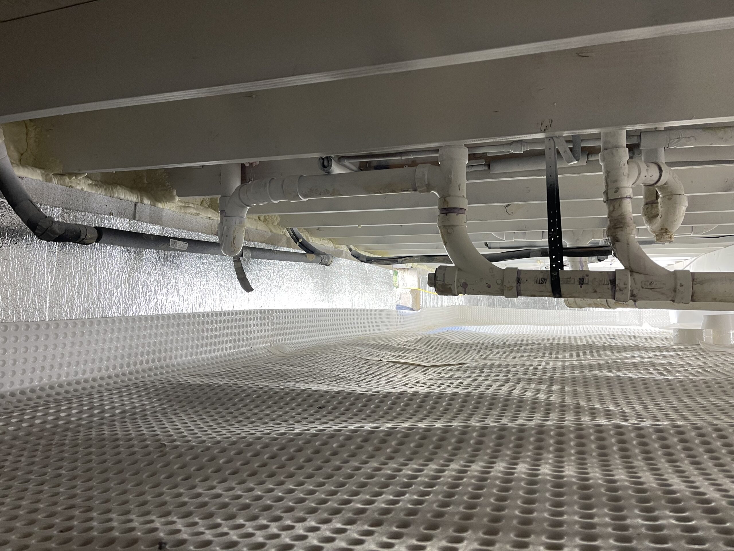 Crawl space with floor lining, insulated walls and exposed floor joists