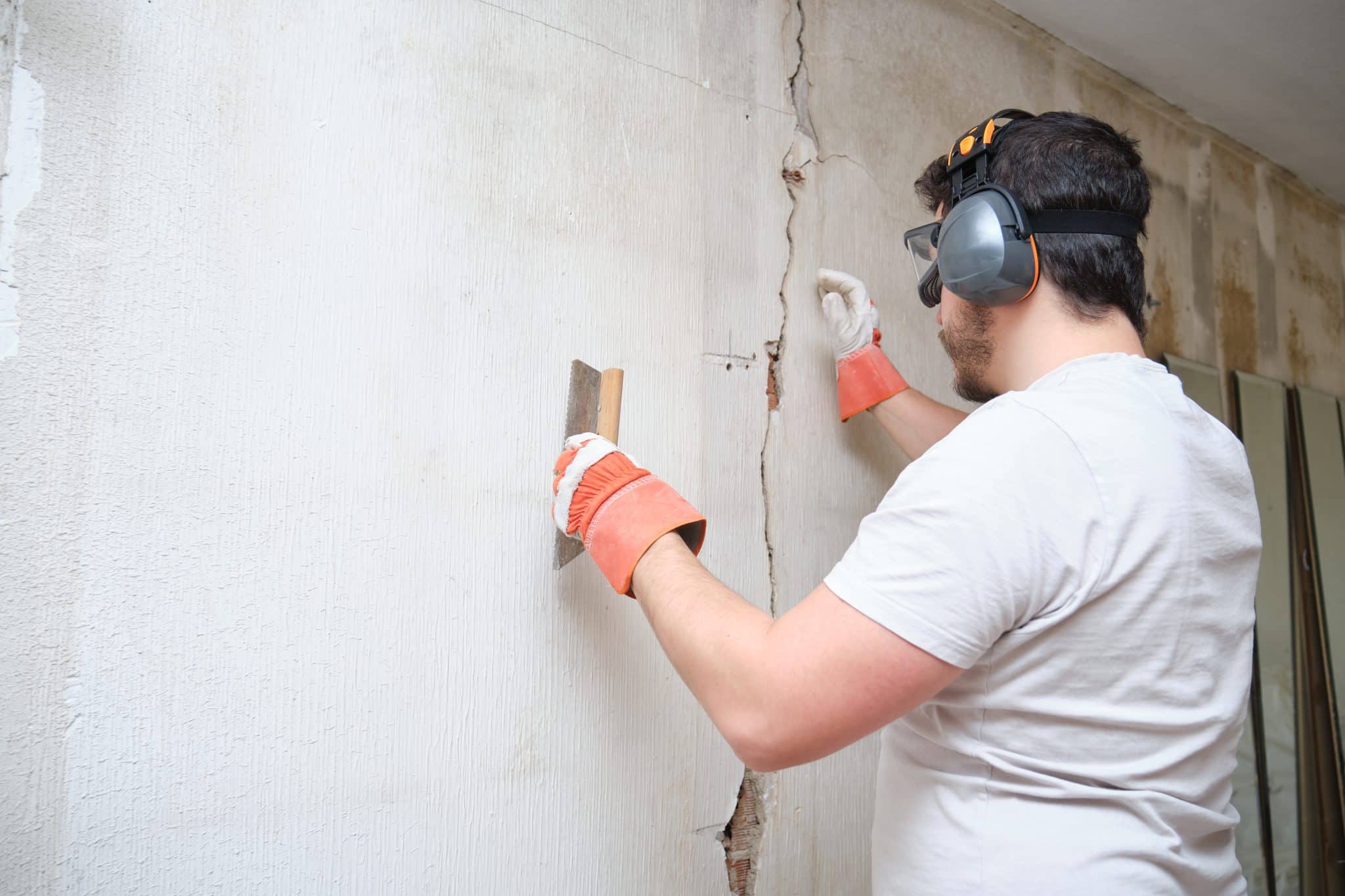Construction worker performing foundation repair and foundation replacement, skillfully repairing a crack in the plastering for a solid and secure structure
