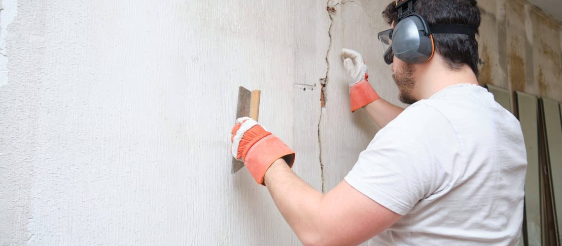 Construction worker performing foundation repair and foundation replacement, skillfully repairing a crack in the plastering for a solid and secure structure