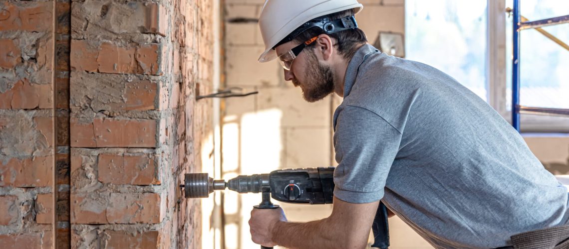 A handy man using a power drill to repair a foundation issue