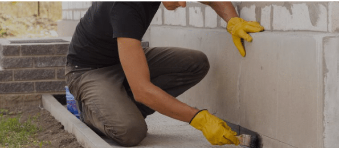 man with gloves repainting home foundation
